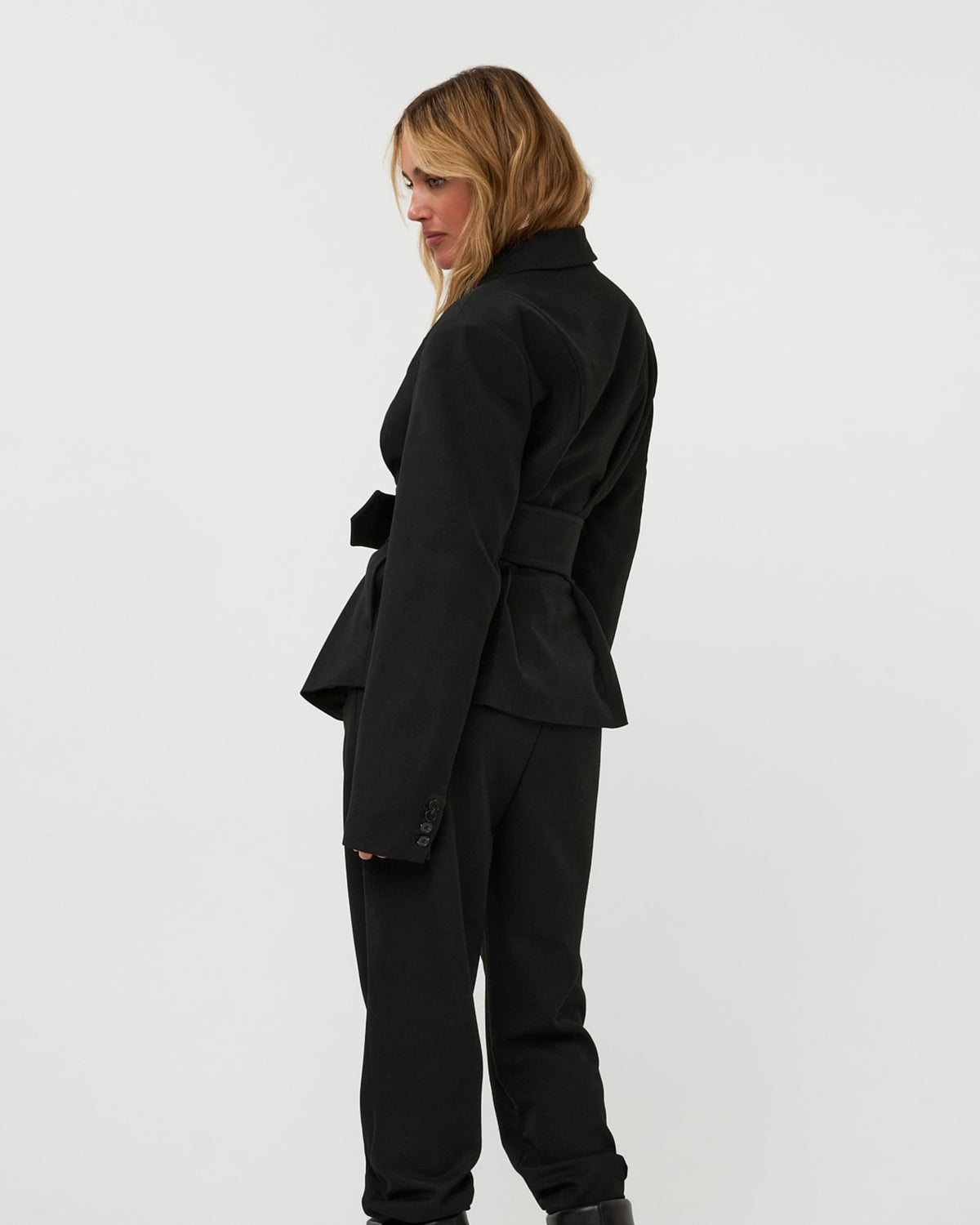 Model wearing the 264-15-1-3-19 black belted blazer and matching trousers against a white background.