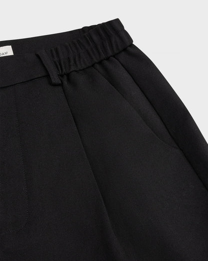 Close-up of the pleated elastic waistband and front pocket of black 264-15-1-3-20 trousers.